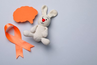 Photo of Orange ribbon, paper brain cutout and toy bunny on light grey background, flat lay with space for text. Multiple sclerosis awareness