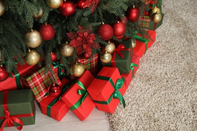 Many gift boxes under decorated Christmas tree in room