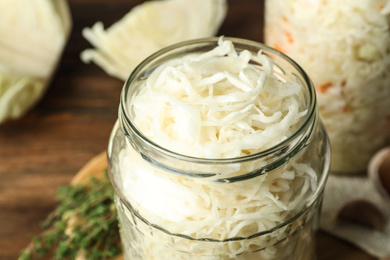 Photo of Jar of tasty fermented cabbage on table, closeup