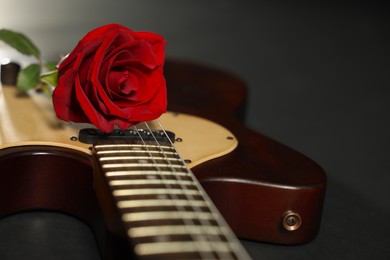 Photo of Beautiful rose and electric guitar on black background, closeup. Space for text