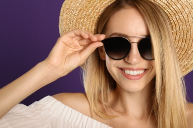 Photo of Beautiful woman in stylish sunglasses on purple background, closeup