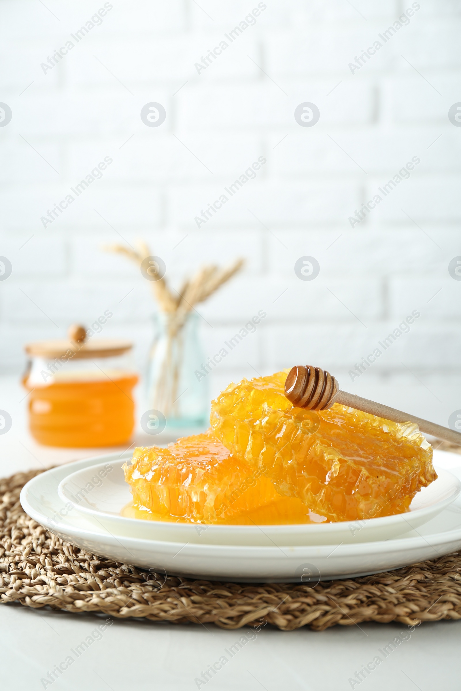 Photo of Natural honeycombs with tasty honey and dipper on white table