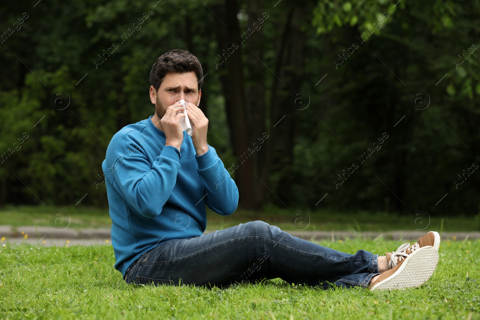 Photo of Man suffering from seasonal spring allergy on green grass in park