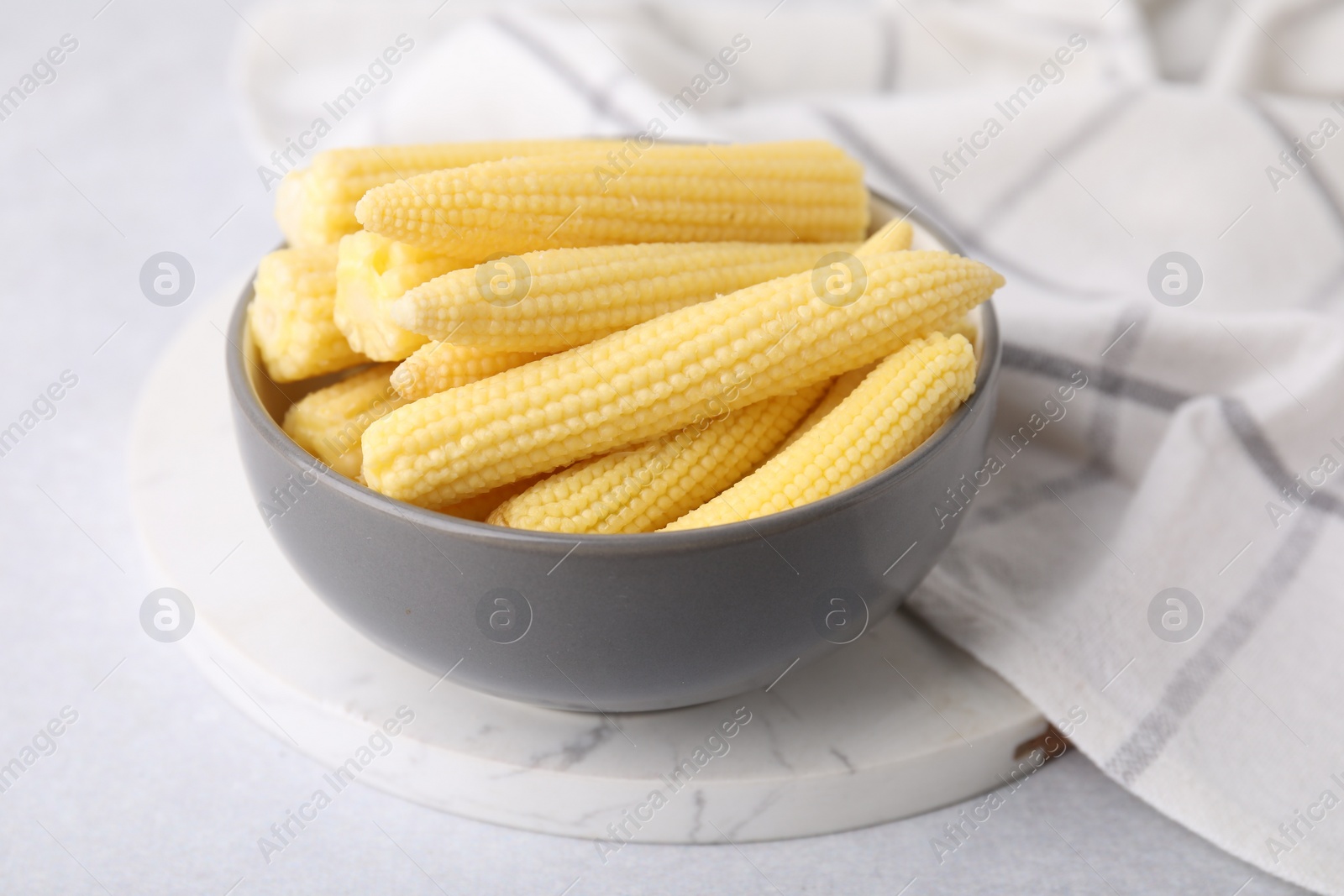 Photo of Tasty fresh yellow baby corns in bowl on white table