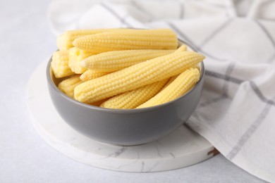 Tasty fresh yellow baby corns in bowl on white table