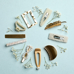 Photo of Frame of stylish hair clips and flowers on light background, flat lay