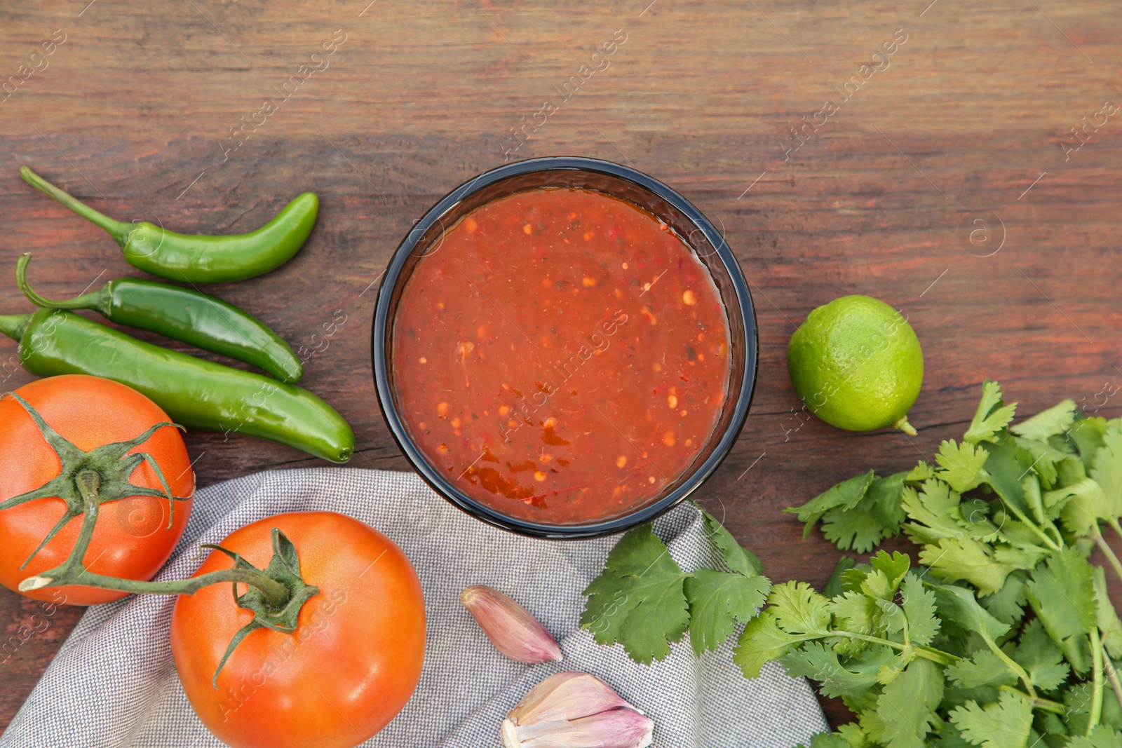 Photo of Flat lay composition of tasty salsa sauce and different ingredients on wooden table