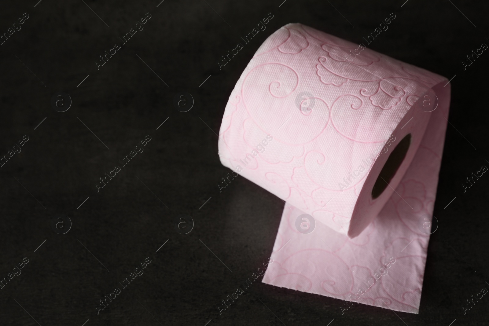 Photo of Soft toilet paper roll on black background. Space for text