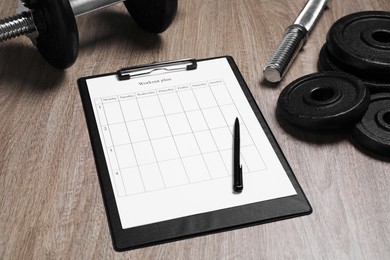Photo of Workout plan, pen and sports equipment on wooden table. Personal training