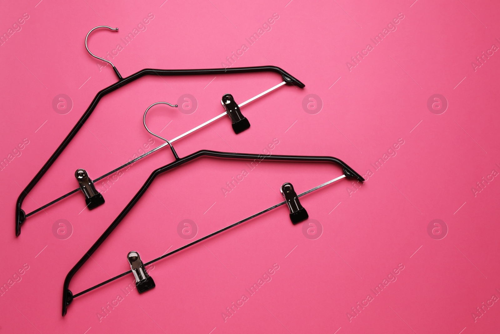 Photo of Empty hangers with clips on pink background, flat lay