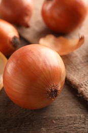 Photo of Many ripe onions on wooden table, closeup