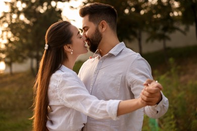 Photo of Lovely couple dancing together outdoors at sunset