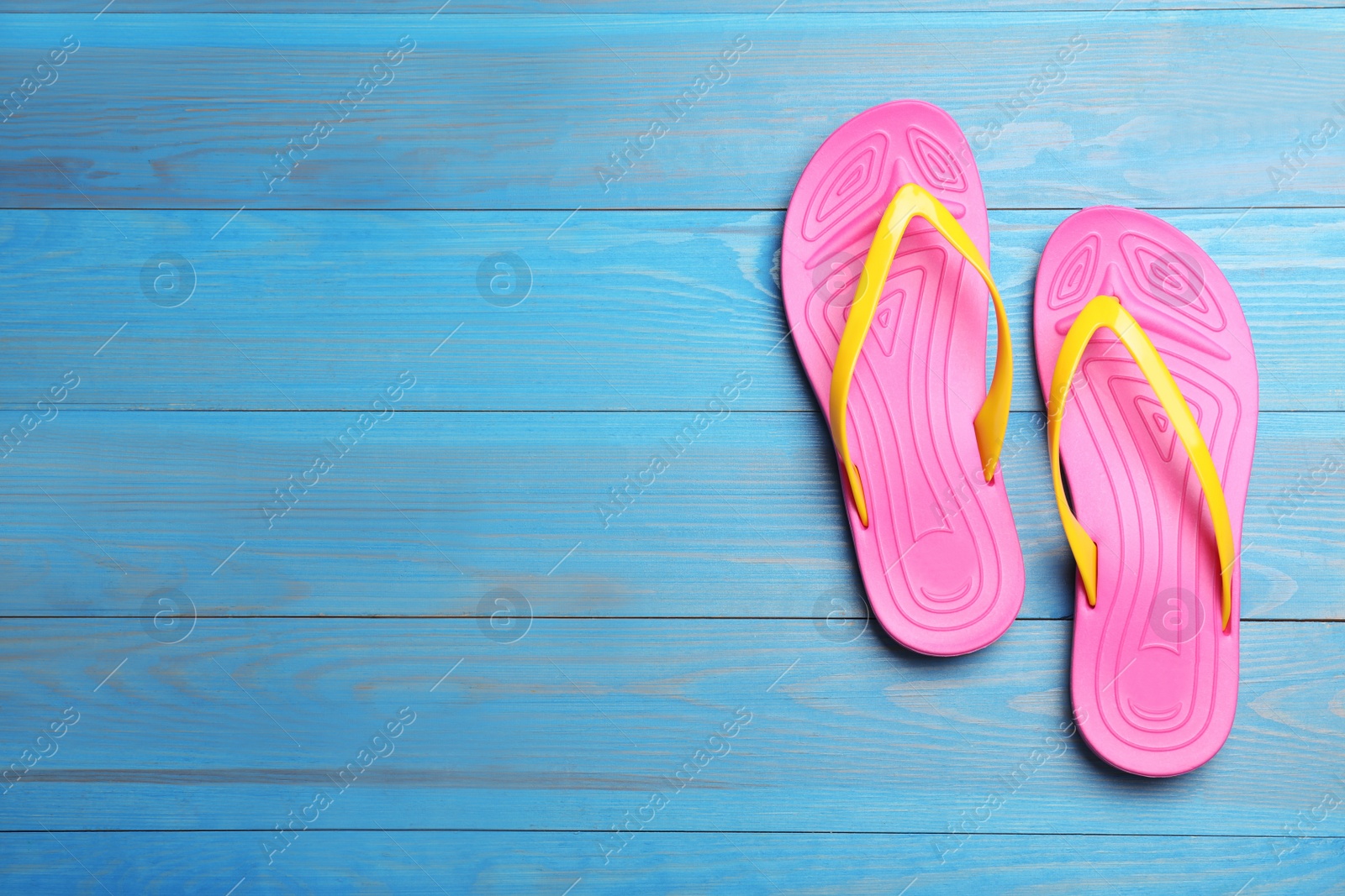 Photo of Stylish beach flip flops on blue wooden background, flat lay. Space for text