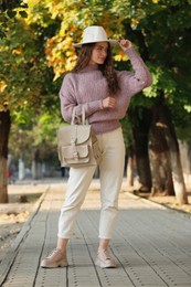 Young woman with stylish beige backpack on city street