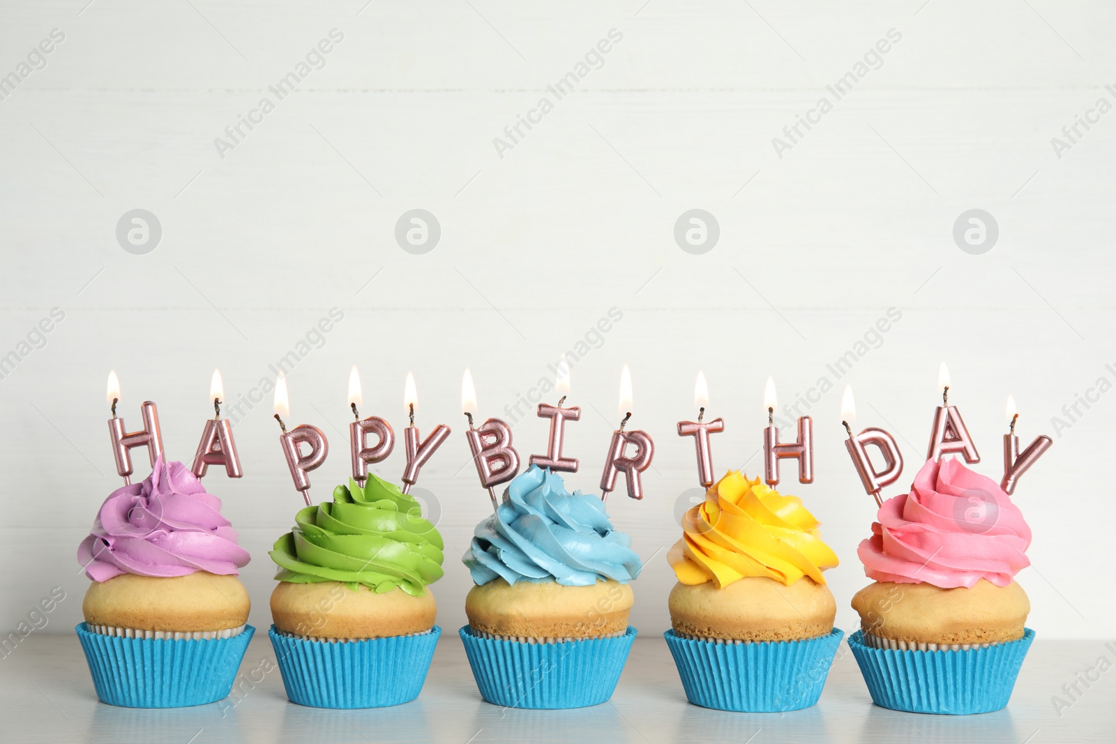 Photo of Birthday cupcakes with burning candles on table against white background. Space for text