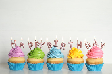 Photo of Birthday cupcakes with burning candles on table against white background. Space for text