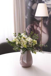 Photo of Vase with beautiful bouquet on white table indoors. Stylish interior element