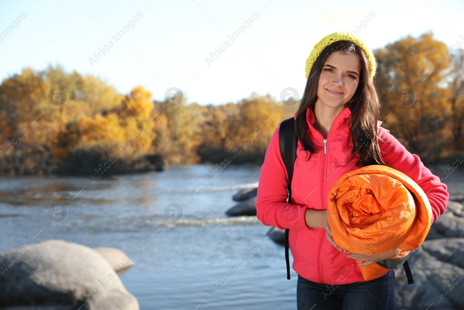 Photo of Female camper with sleeping bag near beautiful lake. Space for text
