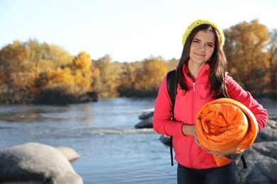 Photo of Female camper with sleeping bag near beautiful lake. Space for text
