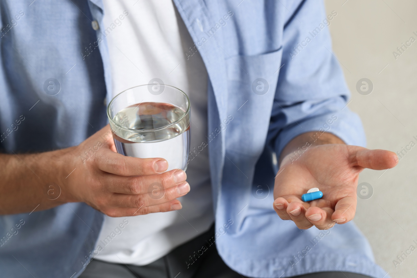 Photo of Man with glass of water and pills, closeup