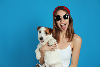 Young woman with her cute Jack Russell Terrier on light blue background. Lovely pet