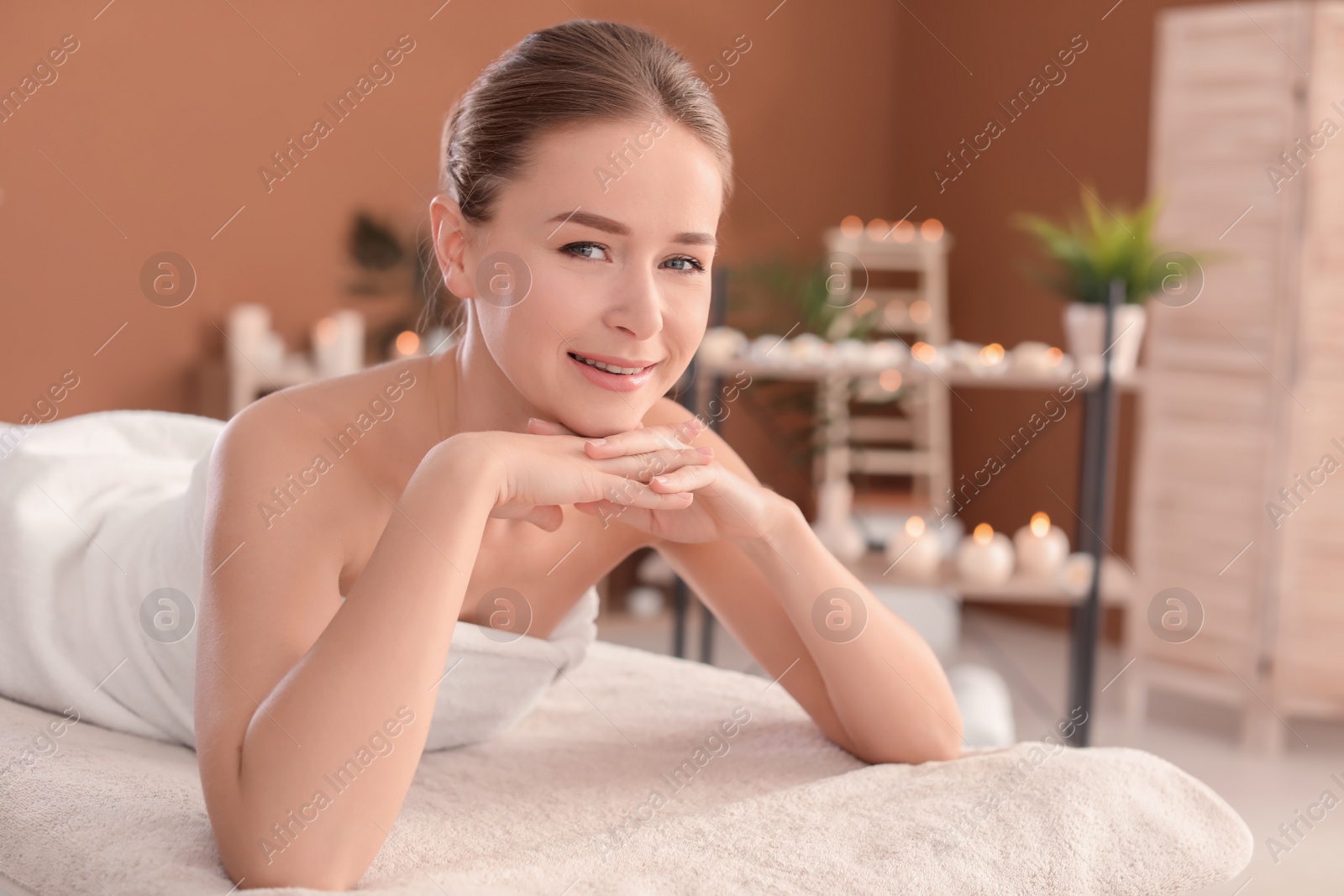 Photo of Young woman lying on massage table in spa salon