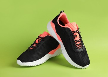 Photo of Pair of comfortable sports shoes on light green background