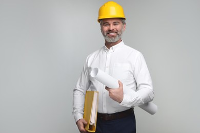Photo of Architect in hard hat holding folder and draft on grey background