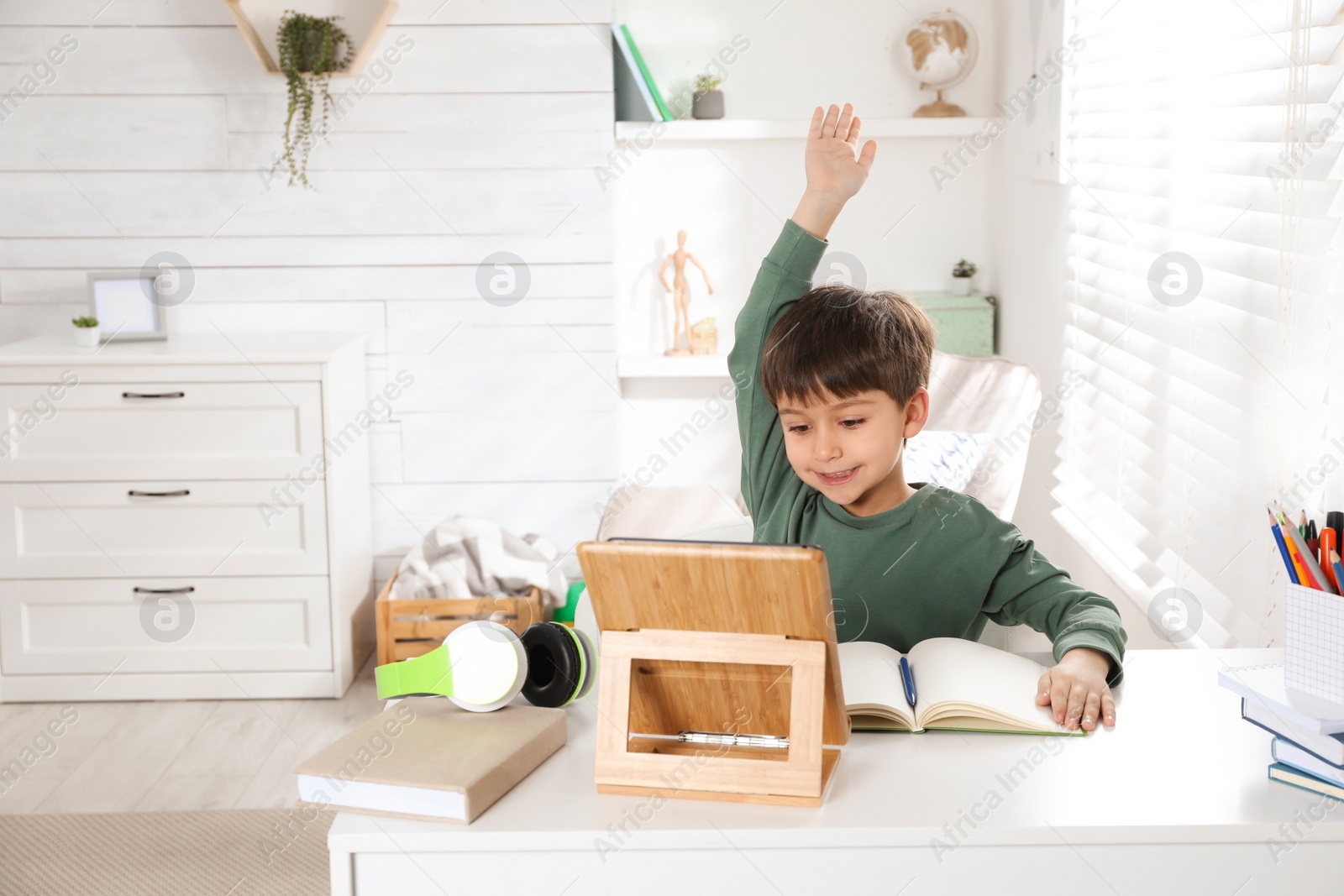 Photo of Cute little boy with modern tablet studying online at home, space for text. E-learning