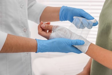 Photo of Doctor bandaging patient's burned hand indoors, closeup
