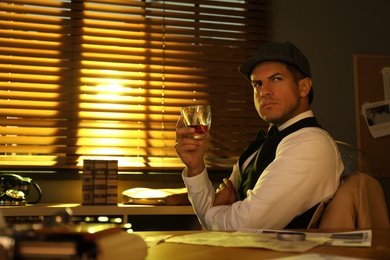 Old fashioned detective with drink at table in office