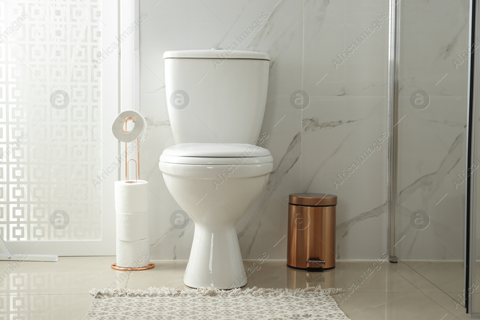 Photo of Toilet bowl near shower stall in modern bathroom interior