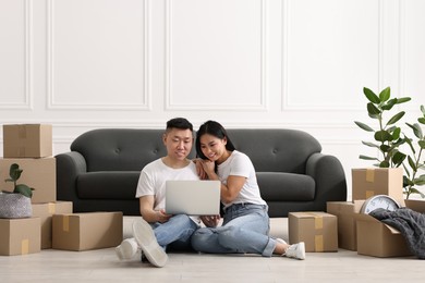 Photo of Happy couple with laptop on floor in their new apartment
