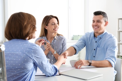 Photo of Real estate agent consulting young couple in office