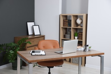 Photo of Stylish office with modern furniture and laptop on wooden desk. Interior design