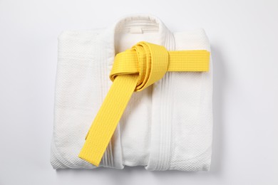 Photo of Yellow karate belt and kimono on white background, top view