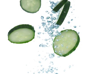 Slices of fresh cucumber under water on white background, closeup. Space for text