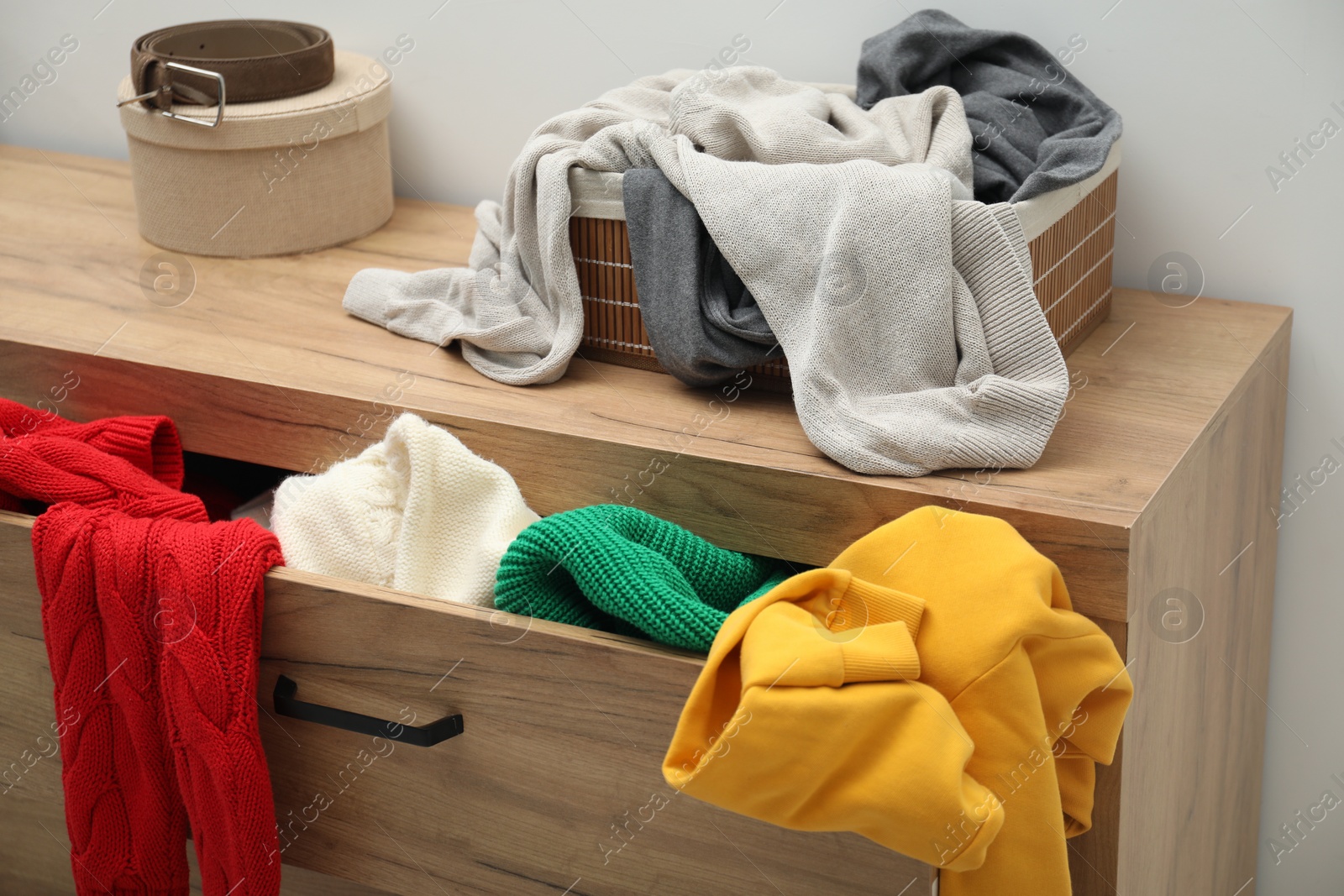 Photo of Cluttered chest of drawers indoors. Clothes in mess