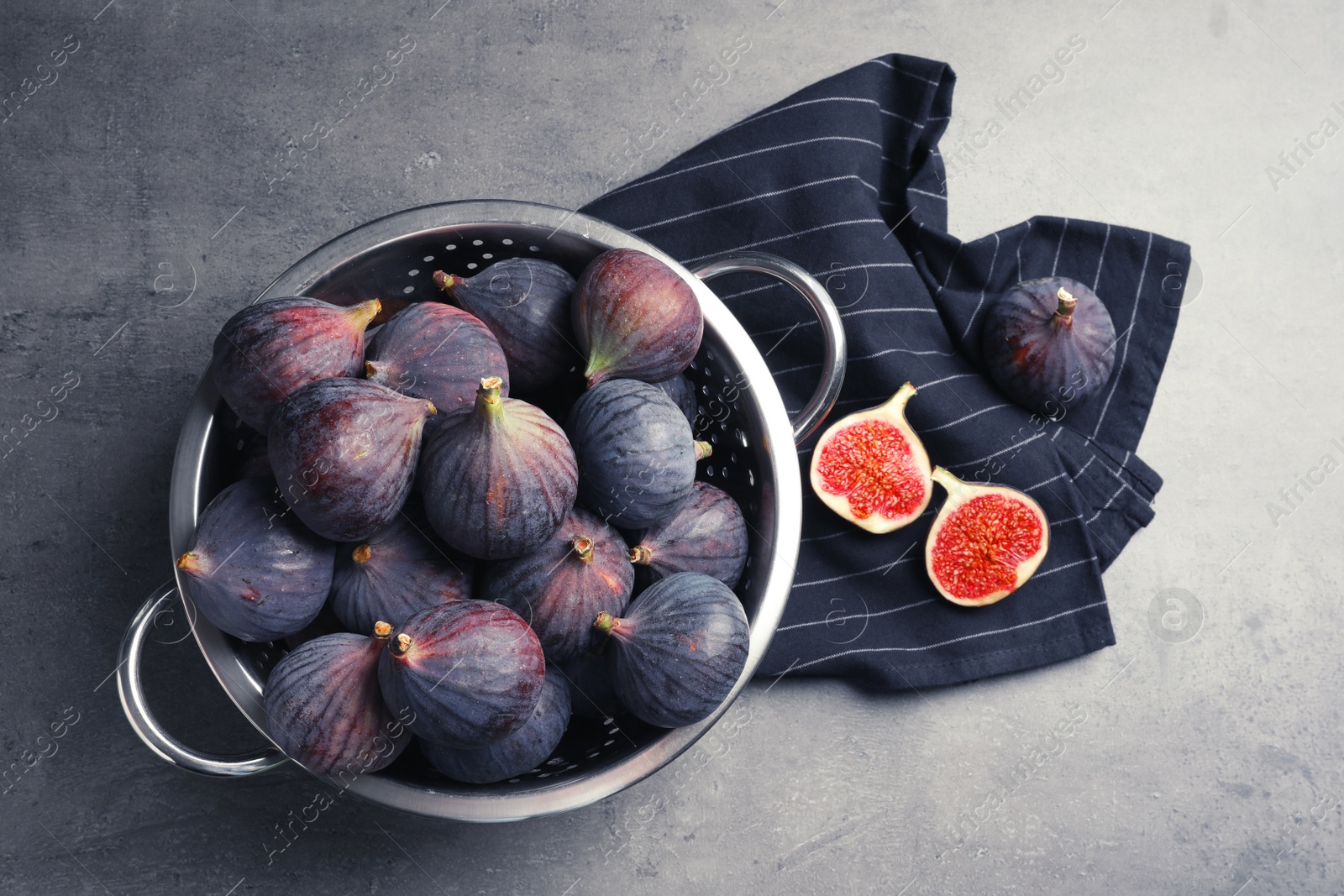 Photo of Colander with fresh ripe figs on gray background, top view