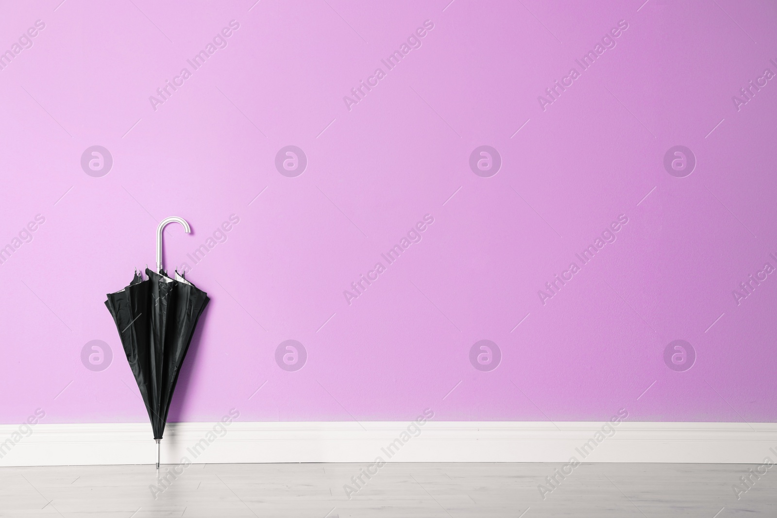 Photo of Beautiful umbrella on floor near color wall with space for design