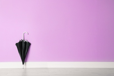 Photo of Beautiful umbrella on floor near color wall with space for design