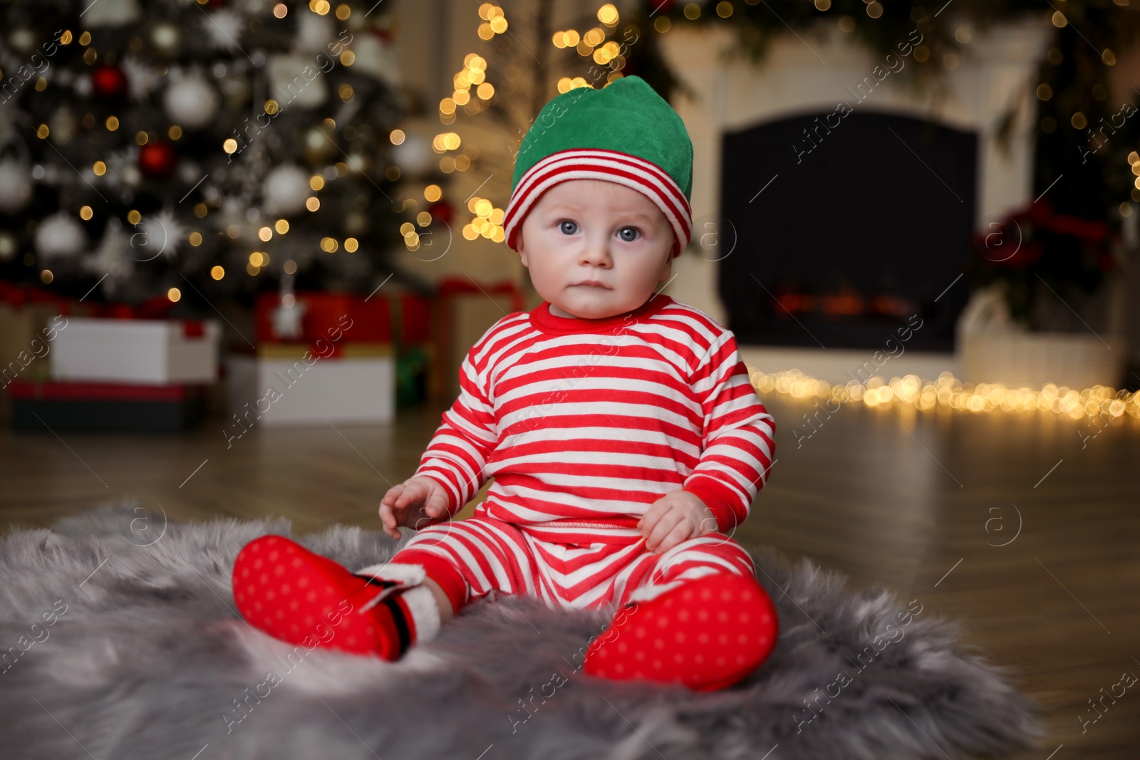 Photo of Cute little baby in Santa's elf clothes on floor at home. Christmas celebration
