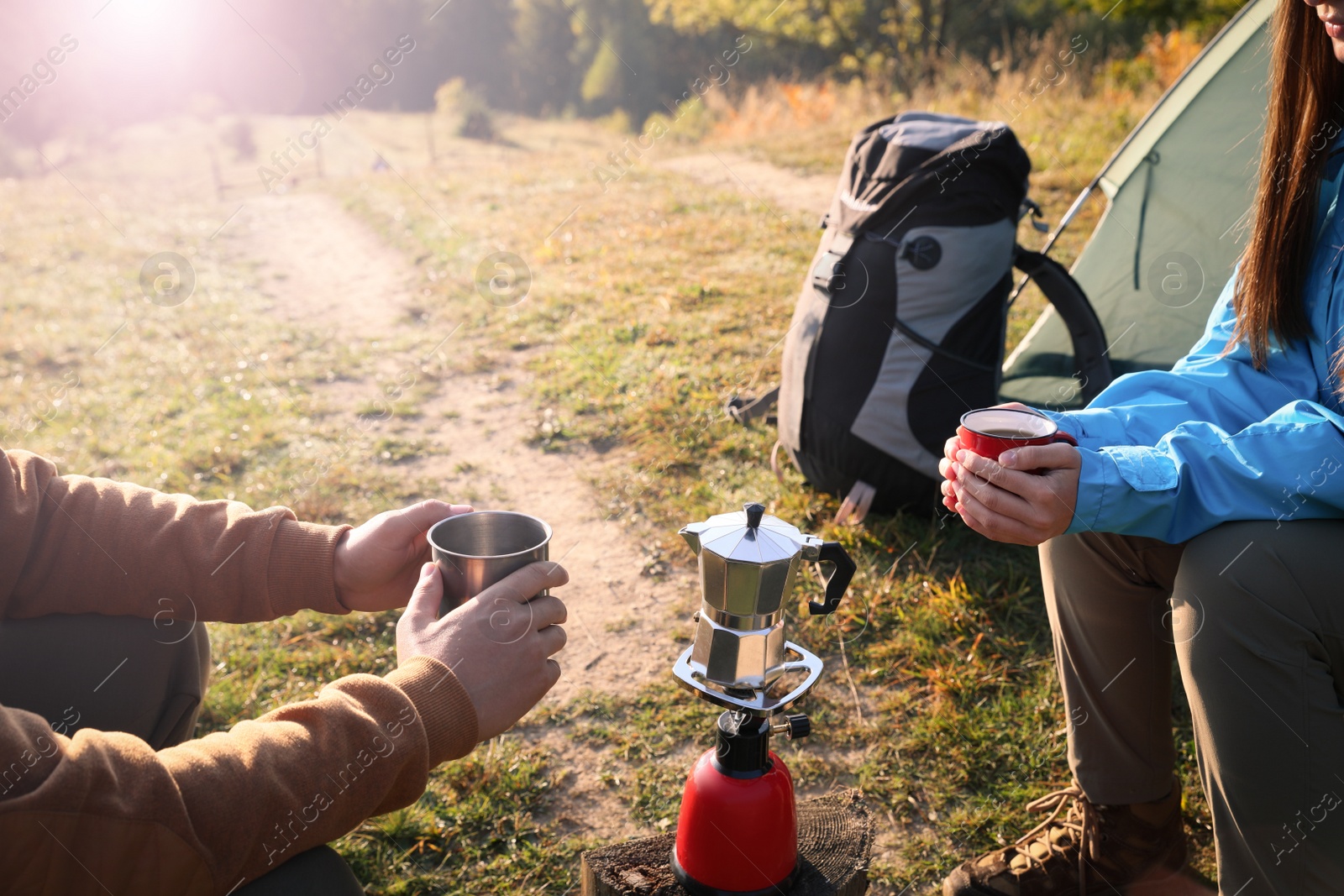 Photo of Young couple drinking coffee near camping tents outdoors, closeup