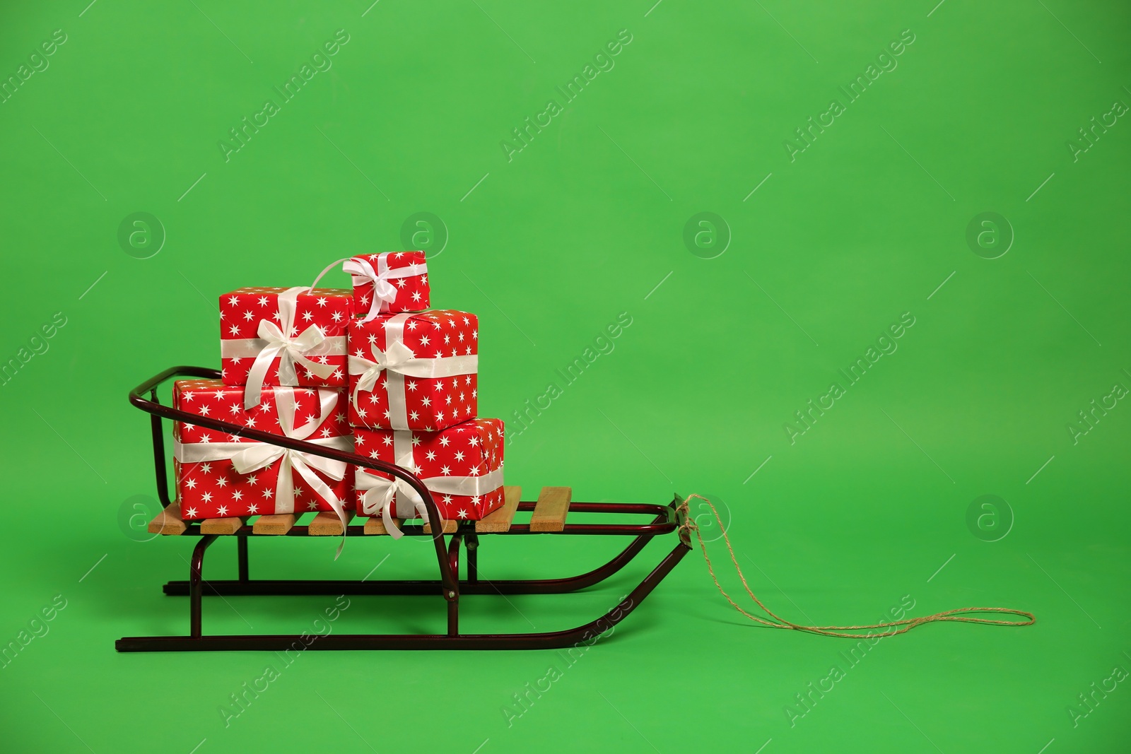 Photo of Sleigh with gift boxes on green background. Space for text