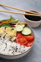 Photo of Delicious poke bowl with vegetables, tofu and mesclun served on light grey table
