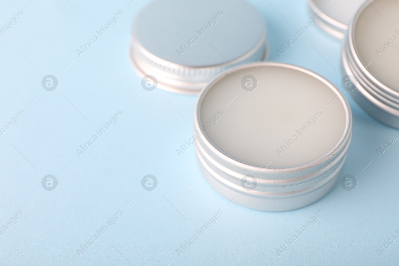 Photo of Lip balms on light blue background, closeup. Space for text