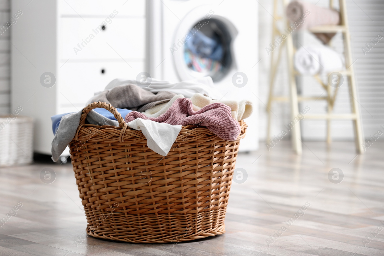 Photo of Wicker basket with dirty laundry on floor indoors, space for text