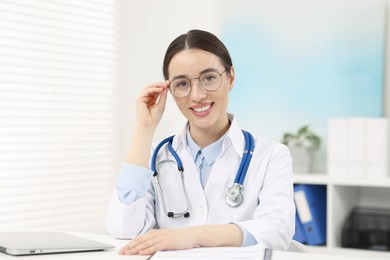 Photo of Medical consultant with glasses and stethoscope at table in clinic