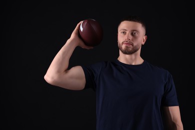 Photo of Athletic young man with American football ball on black background