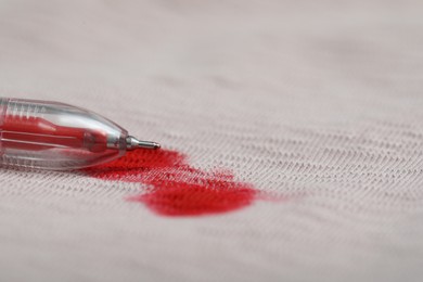 Photo of Pen and stain of red ink on beige shirt, closeup. Space for text